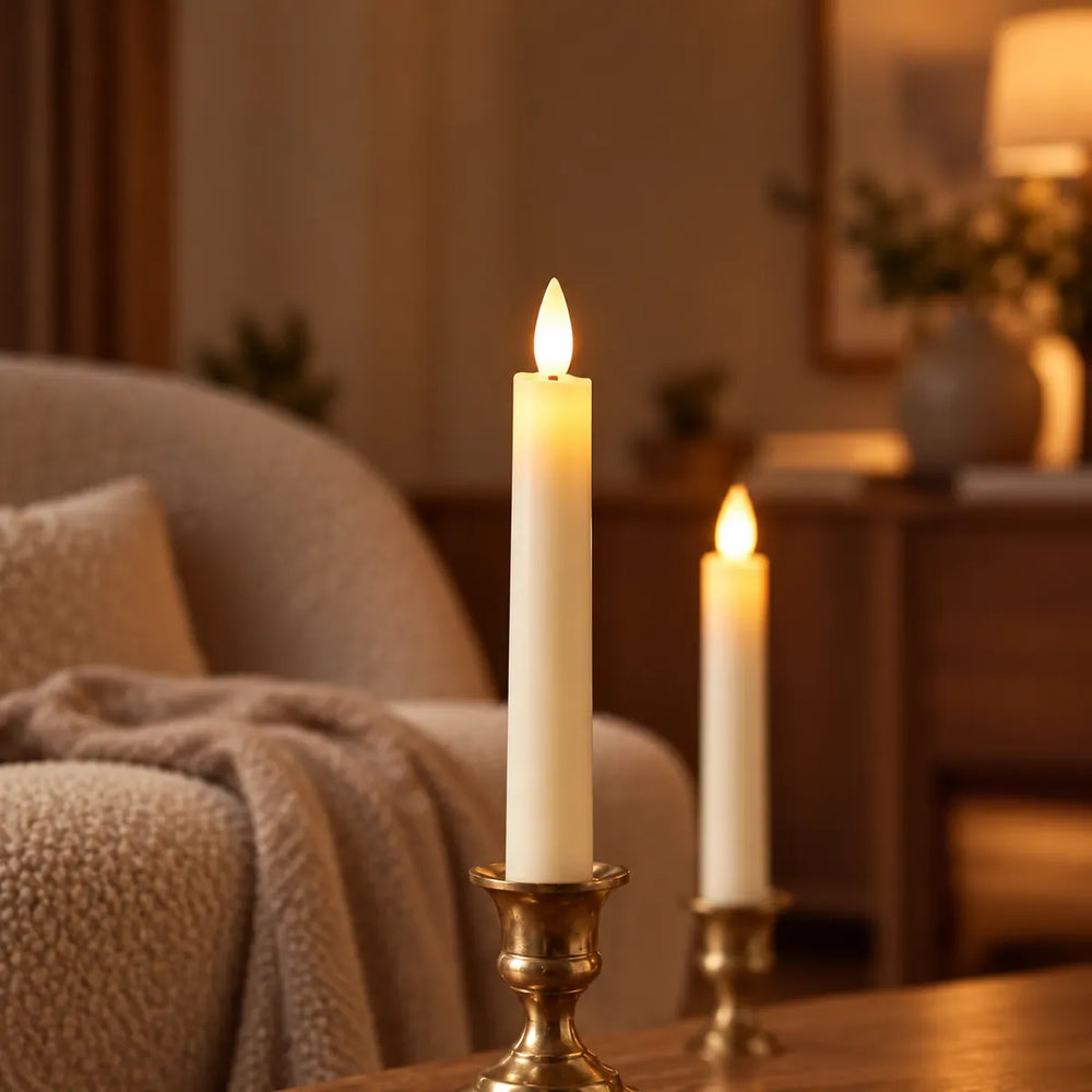 Close-up of a flameless Wove Luma LED taper candle glowing warmly in a brass holder beside an armchair