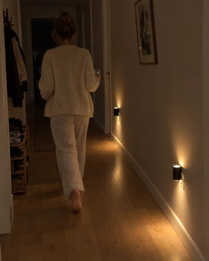 Woman walking through a dark hallway lit by wall lights near the floor