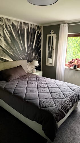 Charcoal grey Wove duvet on a double bed in front of a dark feature wall