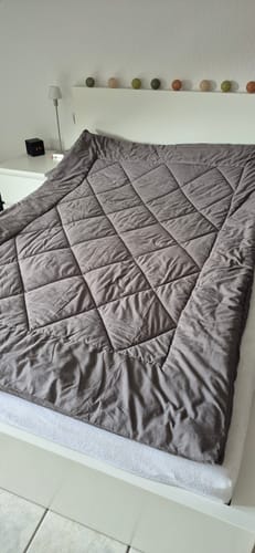Grey-beige Wove duvet folded back on a white bed with fairy lights above
