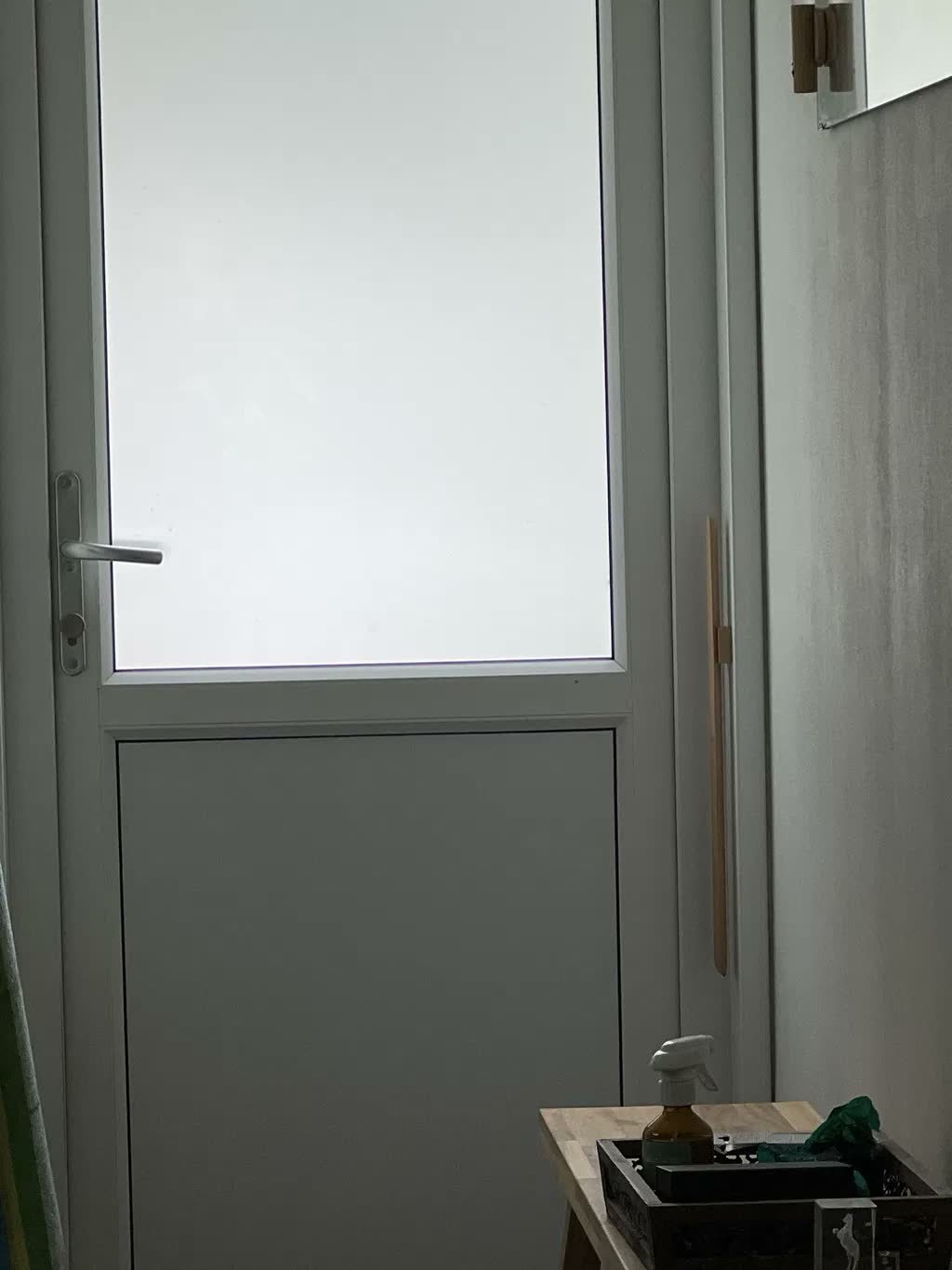 Natural beech shoehorn on a greige wall beside a white garden door with frosted glass