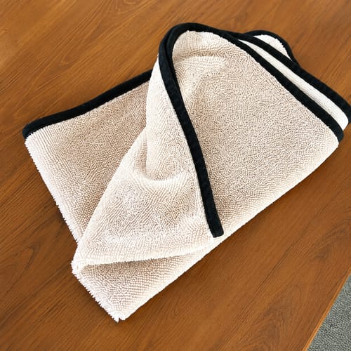 Beige Wove microfibre cloth folded on a wooden worktop