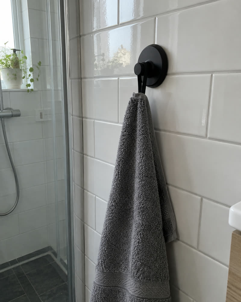 Matte black Wove hook on white tile with a grey towel